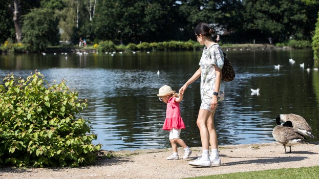 Woman and child walking on a path alongside a lake in August at Dunham Massey, Cheshire